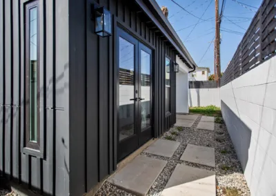 A small backyard with a black door and black siding.