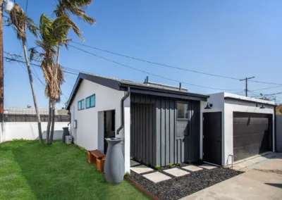 A small house with a garage and palm trees.