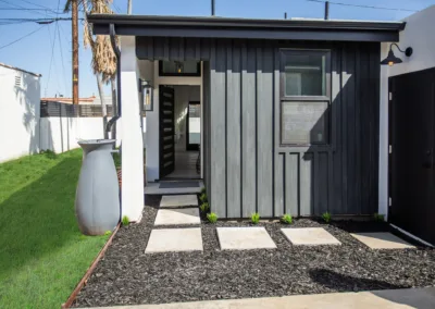 A small house with a black door and gravel path.