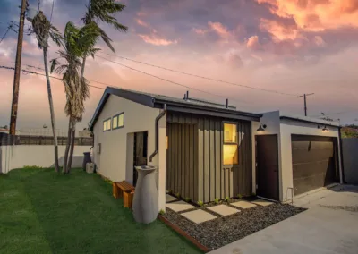 A small house with a garage and palm trees.