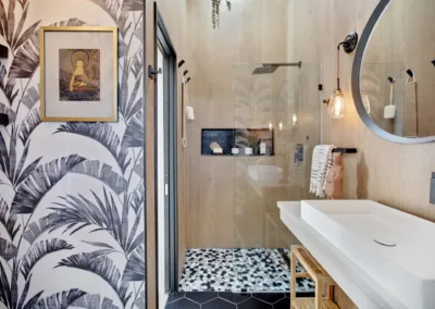 A black and white bathroom with a palm tree wallpaper.